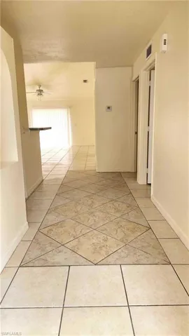 Hall featuring light tile patterned floors and baseboards
