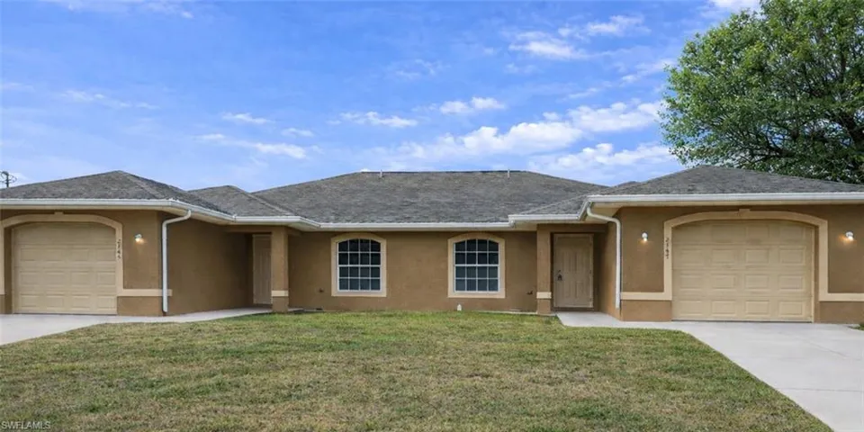 Single story home featuring a garage, stucco siding, a front yard, and driveway