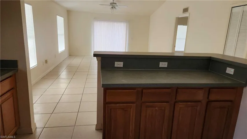 Kitchen featuring dark countertops, light tile patterned floors, and a ceiling fan