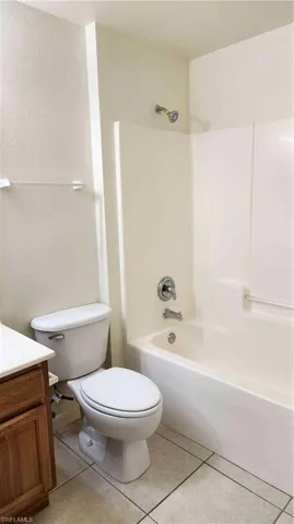 Full bathroom featuring vanity, shower / washtub combination, light tile patterned floors, and a textured wall