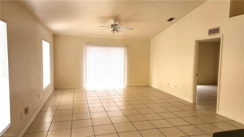 Spare room with ceiling fan, lofted ceiling, healthy amount of natural light, and light tile patterned floors