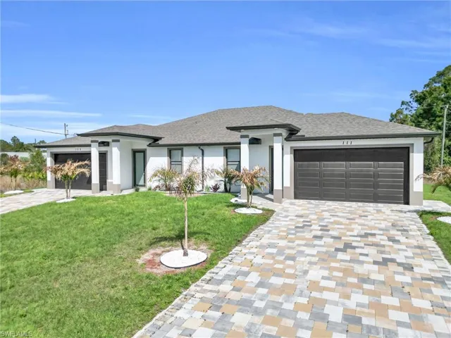 Prairie-style home with a front yard, a garage, driveway, stucco siding, and roof with shingles