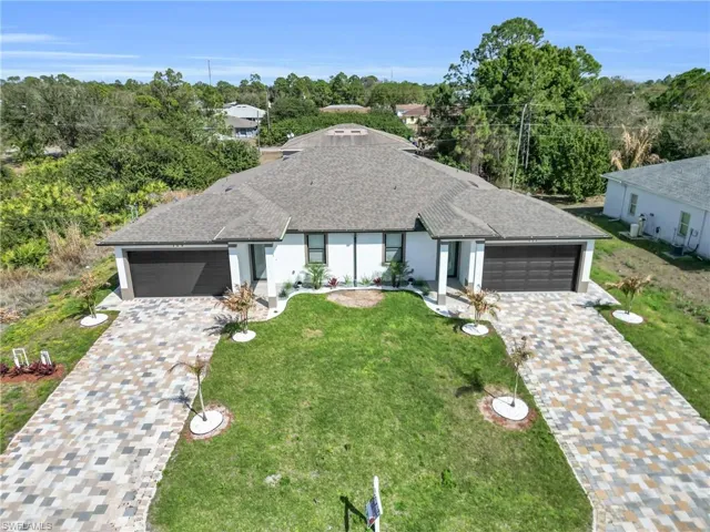 View of front of home with a garage, roof with shingles, stucco siding, and decorative driveway