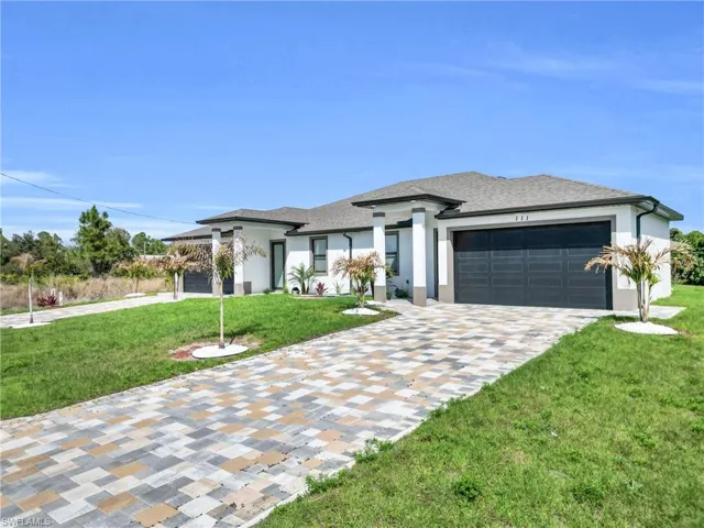 Prairie-style house featuring a front yard, a garage, driveway, stucco siding, and a shingled roof