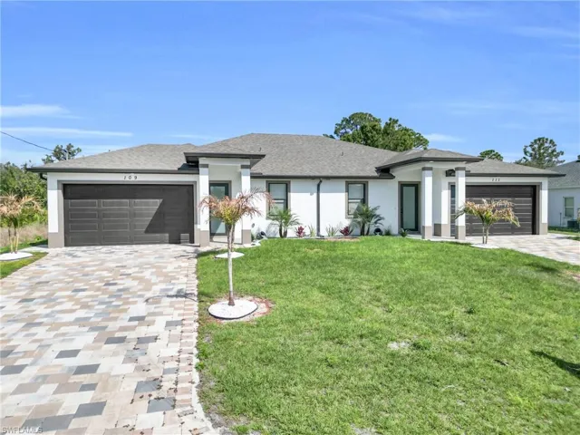 Prairie-style house with an attached garage, stucco siding, decorative driveway, a front lawn, and a shingled roof