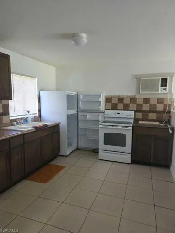 Kitchen featuring dark-toned cabinetry, ceramic tile flooring, a white porcelain drop-in sink, and a decorative checkerboard tile backsplash