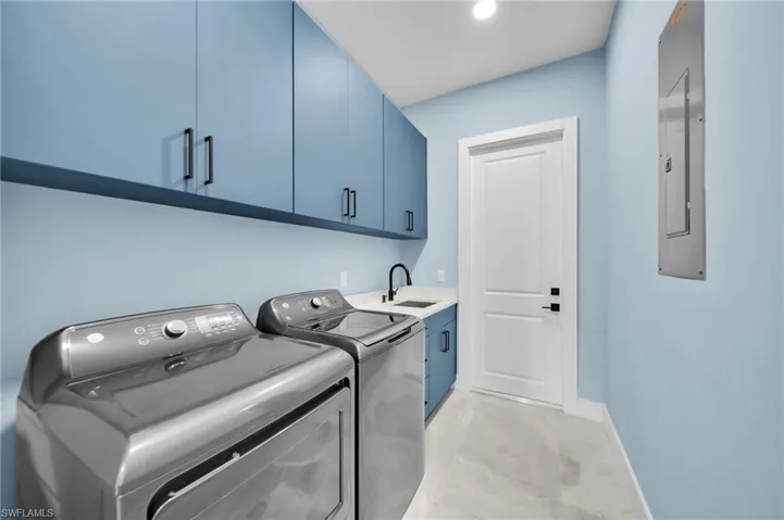 Laundry room with washing machine and clothes dryer, cabinet space, and electric panel