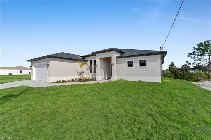 Prairie-style home with a front lawn, stucco siding, and decorative driveway