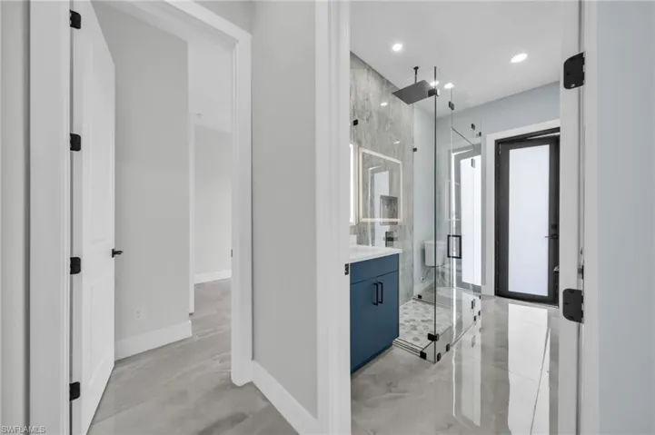 Bathroom featuring a marble finish shower, vanity, and recessed lighting