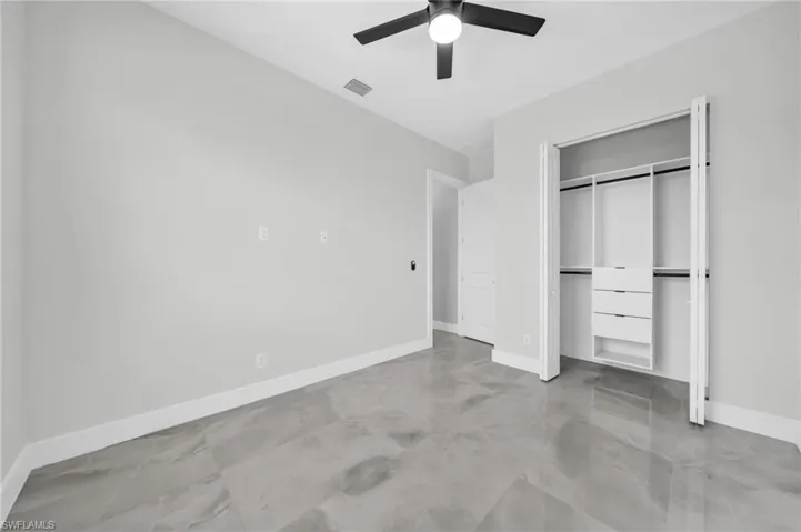Unfurnished bedroom featuring a closet, ceiling fan, and finished concrete floors
