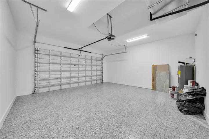 Garage featuring baseboards and electric water heater