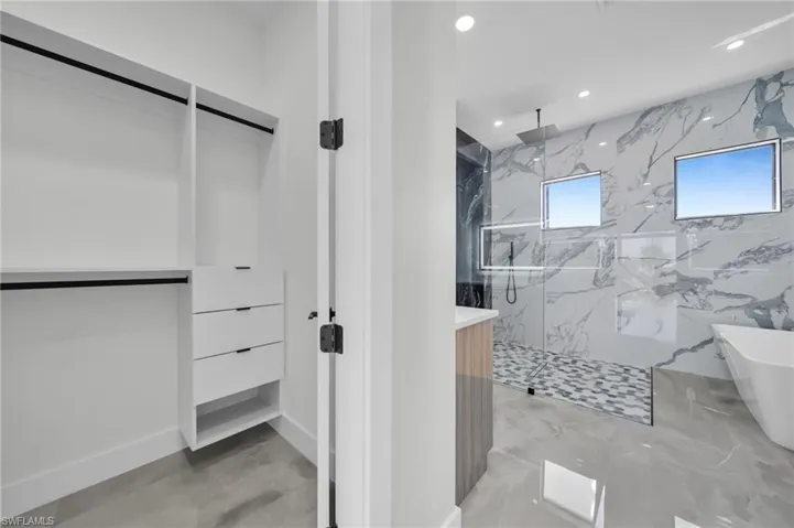 Full bath featuring a marble finish shower, a freestanding tub, recessed lighting, vanity, and light marble finish floors