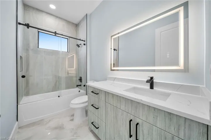 Bathroom with vanity, combined bath / shower with glass door, recessed lighting, and light marble finish floors