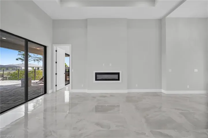 Unfurnished living room featuring a glass covered fireplace and a high ceiling