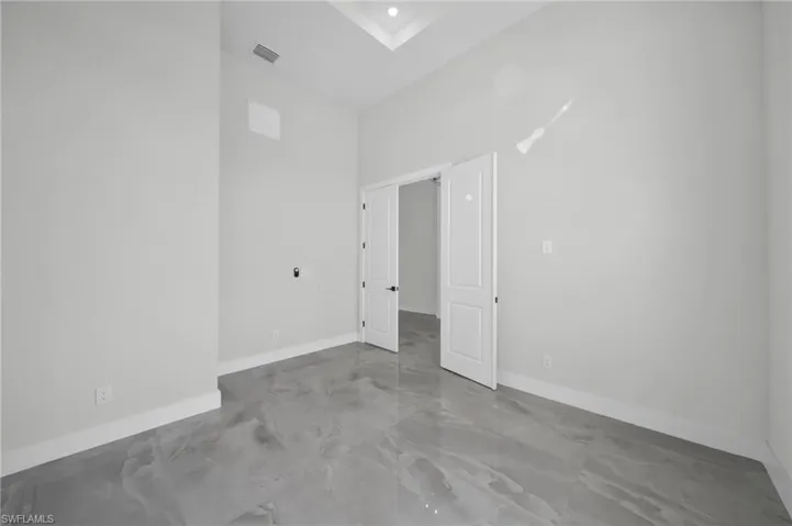 Unfurnished room with baseboards and a high ceiling