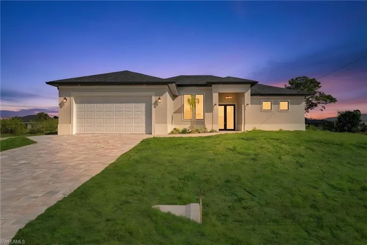 Prairie-style house with a front yard, an attached garage, stucco siding, and driveway