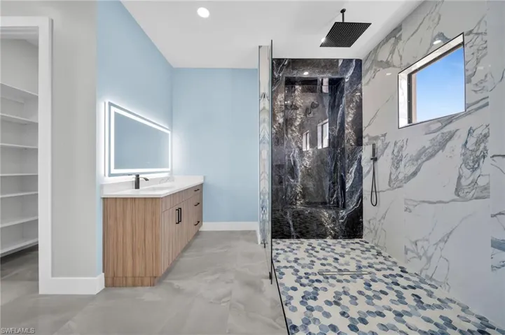 Full bathroom featuring vanity, a marble finish shower, and finished concrete floors