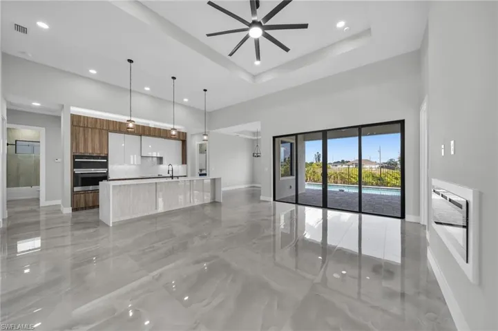 Unfurnished living room with a ceiling fan, light marble finish floors, a high ceiling, and recessed lighting