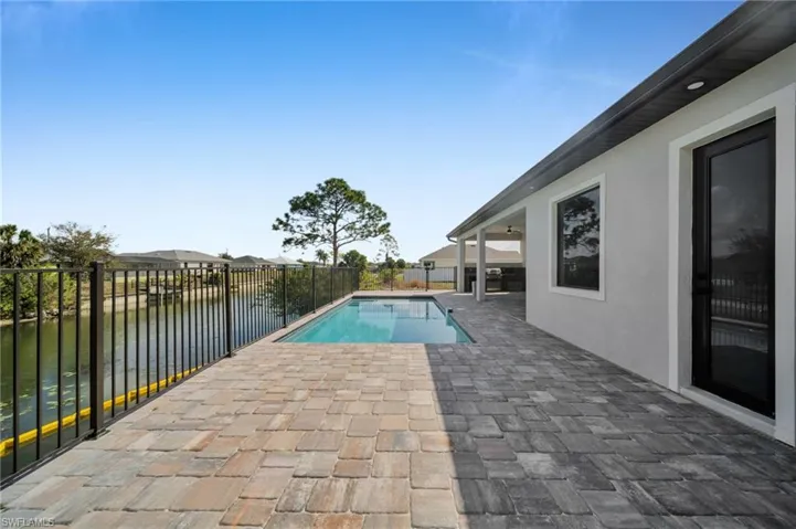 View of pool with patio surround, a fenced backyard, and a water view