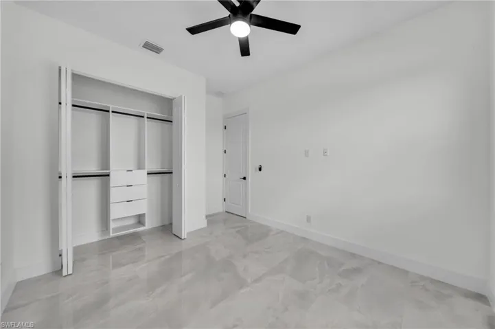 Unfurnished bedroom featuring a closet, a ceiling fan, and light marble finish floors