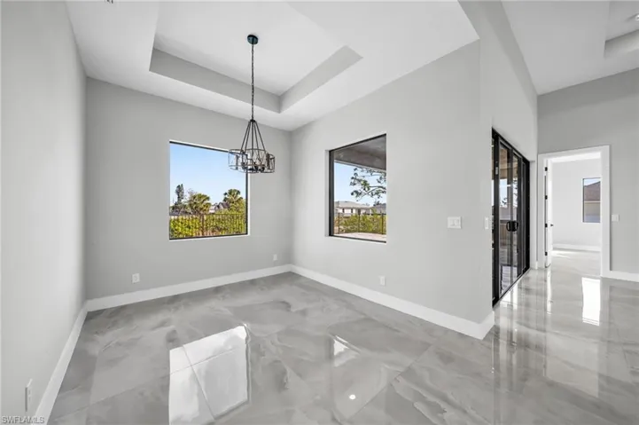 Unfurnished dining area with a raised ceiling and a chandelier
