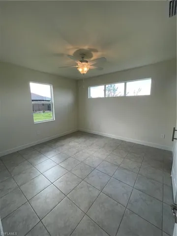 Tiled empty room featuring ceiling fan and a healthy amount of sunlight