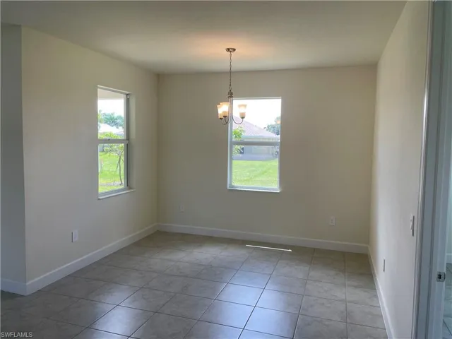 Tiled spare room with a notable chandelier