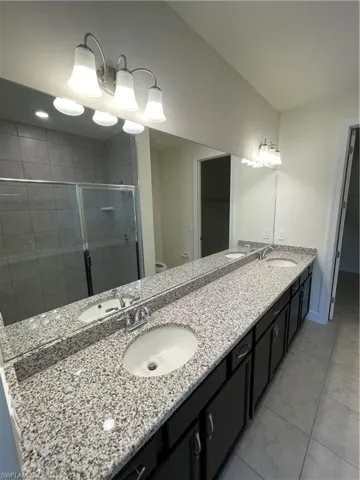 Bathroom featuring a shower with door, vanity, toilet, and tile patterned floors
