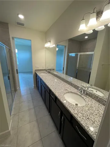 Bathroom featuring tile patterned flooring, walk in shower, and vanity