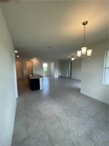 Unfurnished living room with light tile patterned floors and an inviting chandelier