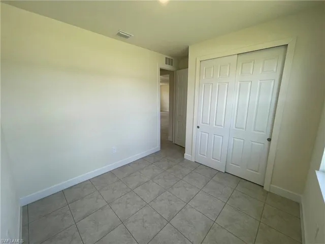 Unfurnished bedroom with light tile patterned flooring and a closet
