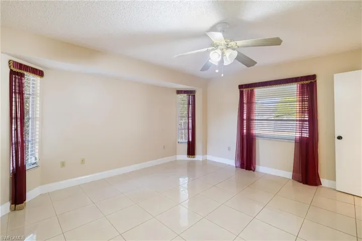 Tiled empty room with ceiling fan and a textured ceiling