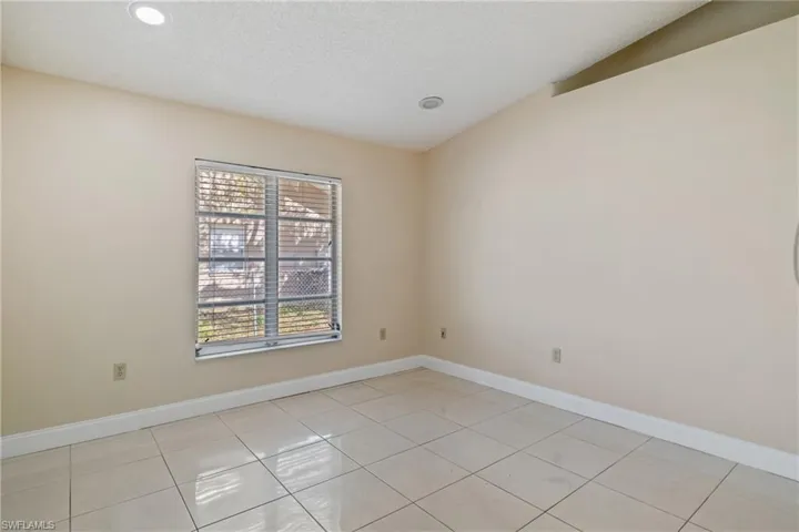 Empty room with baseboards, a textured ceiling, and light tile patterned flooring