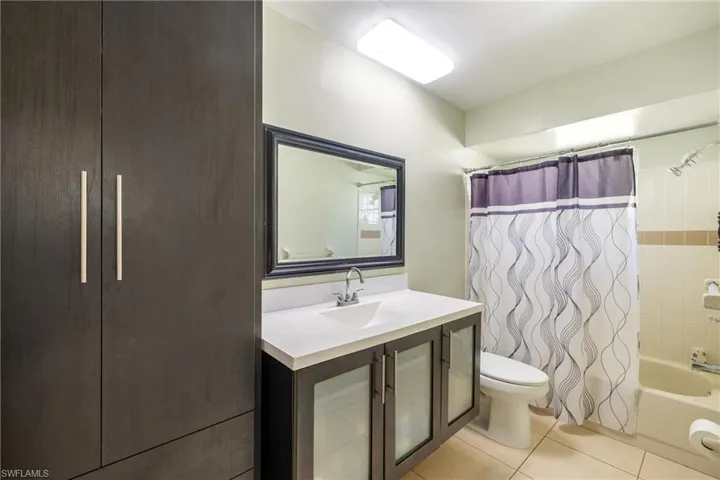 Full bathroom with tile patterned flooring, shower / bath combo, toilet, and vanity