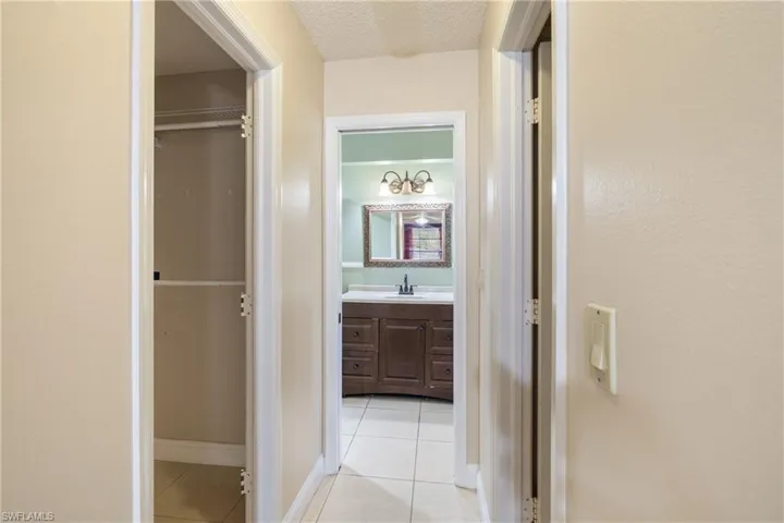 Hall with a textured ceiling, light tile patterned flooring, and sink