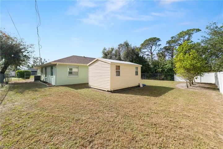 Rear view of property with central air condition unit and a lawn