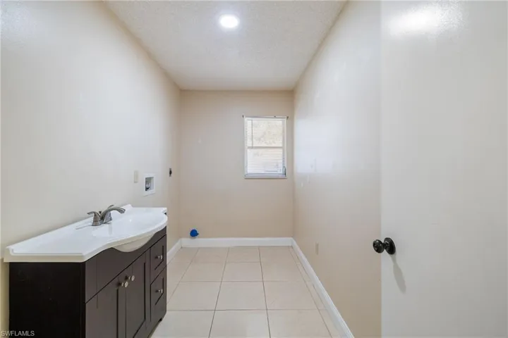 Laundry area with sink, cabinets, washer hookup, electric dryer hookup, and a textured ceiling