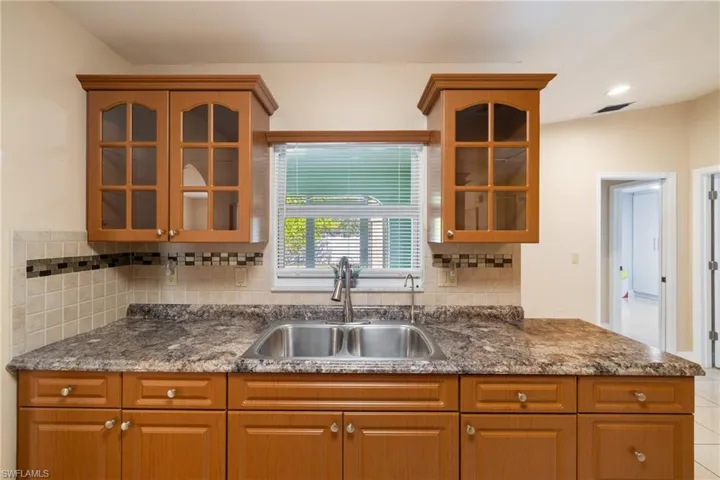 Kitchen featuring decorative backsplash, lofted ceiling, and sink