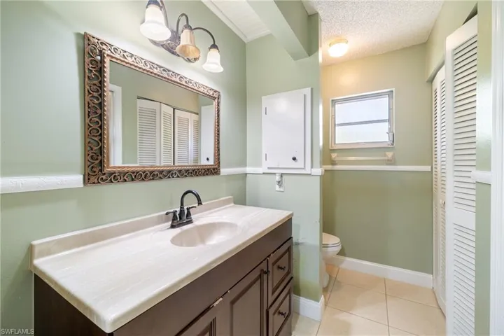 Bathroom featuring tile patterned flooring, a textured ceiling, vanity, and toilet