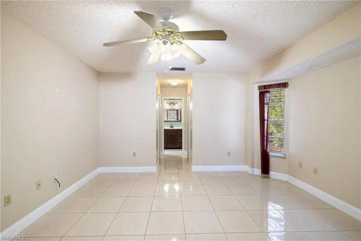 Unfurnished room featuring ceiling fan, light tile patterned flooring, and a textured ceiling