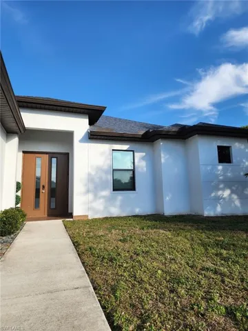 Entrance to property with a garage and a lawn