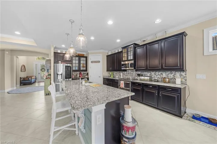 Kitchen with crown molding, glass insert cabinets, a kitchen bar, tasteful backsplash, and arched walkways
