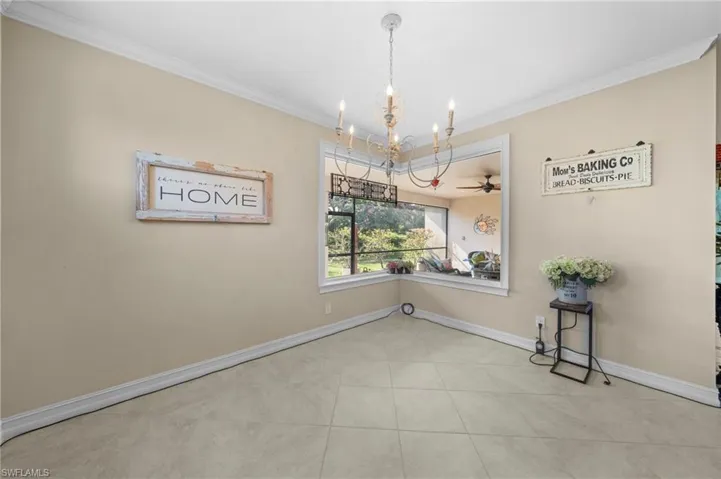 Spare room featuring a chandelier, ornamental molding, ceiling fan, and light tile patterned flooring