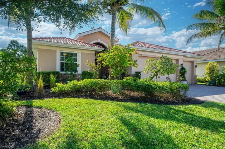 Mediterranean / spanish-style home featuring an attached garage, stucco siding, decorative driveway, a tiled roof, and a front yard