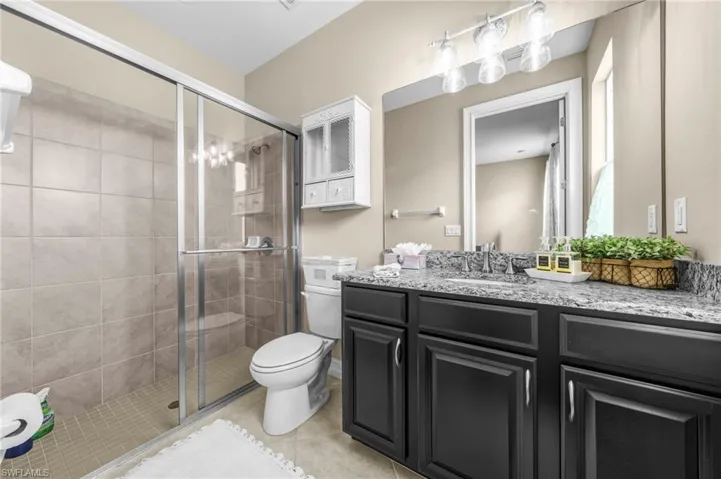 Full bath with vanity, a shower stall, and light tile patterned flooring