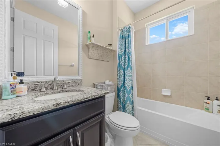 Full bathroom featuring vanity, shower / tub combo with curtain, and light tile patterned floors