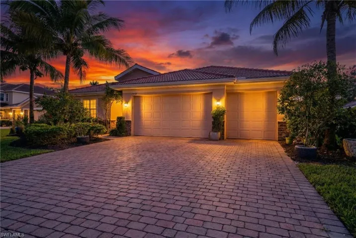 View of front with a garage, decorative driveway, a tile roof, and stucco siding