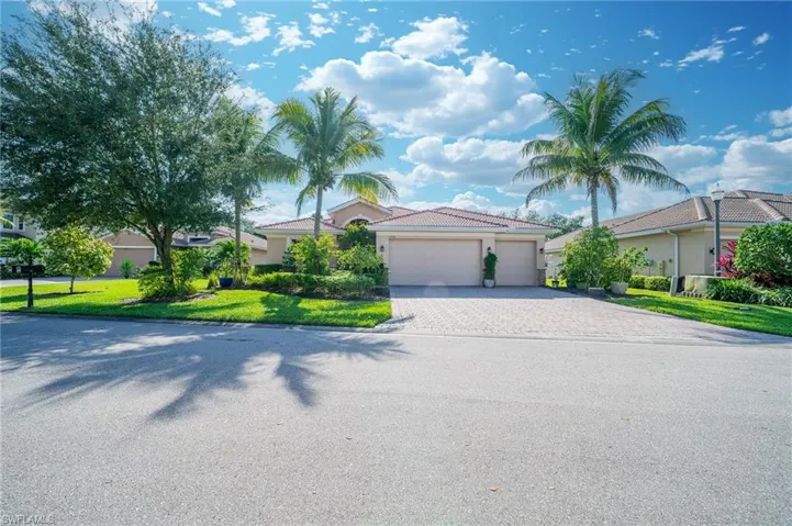 View of front of property with a garage, stucco siding, decorative driveway, and a front lawn
