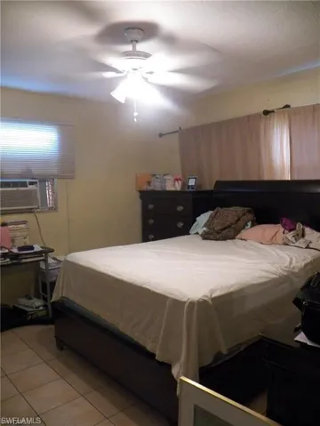 Bedroom featuring light tile patterned flooring, cooling unit, and ceiling fan