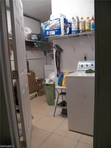 Clothes washing area featuring light tile patterned floors and washer / clothes dryer